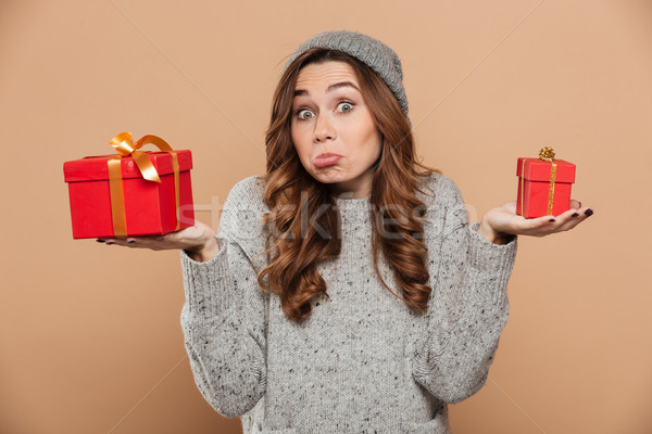 Funny confused brunette girl in woolen hat and jersey holding tw Stock photo © deandrobot