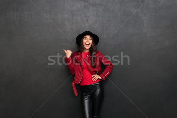 Happy young pretty woman wearing hat pointing to copyspace. Stock photo © deandrobot