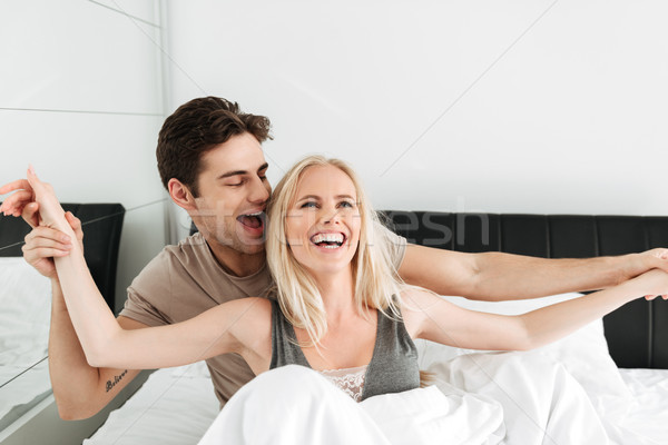 Cheerful funny lovers hugging in bed and laughing Stock photo © deandrobot