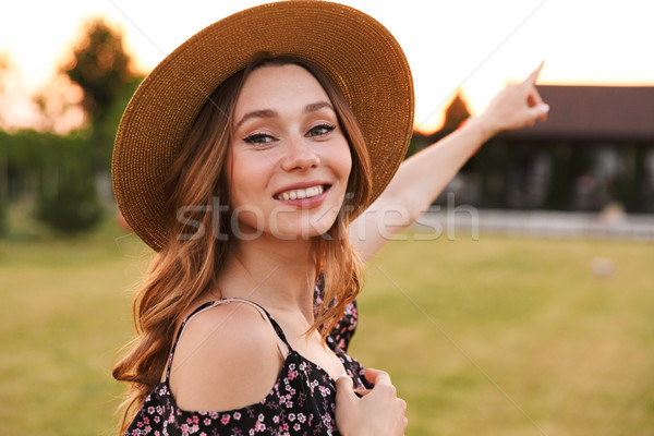 Photo of joyous pretty woman wearing straw hat smiling, and walk Stock photo © deandrobot