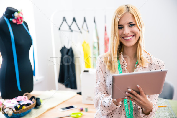 Happy female tailor holding tablet computer  Stock photo © deandrobot