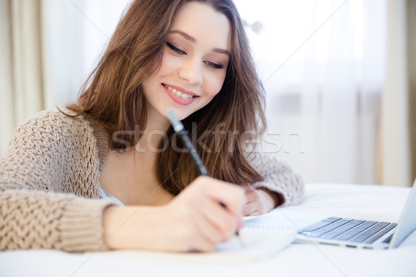 Beautiful inspired smiling young woman writing in notepad  Stock photo © deandrobot