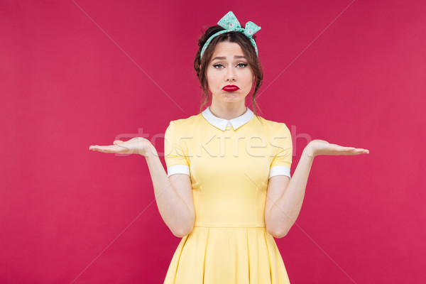 Sad pinup girl standing and holding copyspace on both palms Stock photo © deandrobot