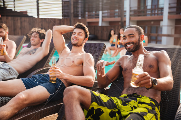 Men having fun in swimming pool and drinking beer Stock photo © deandrobot