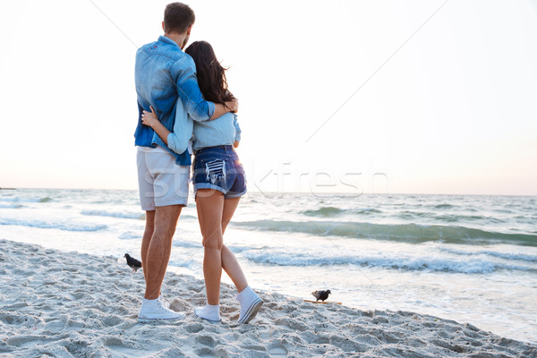Back view of young couple enjoying sunrise on the beach Stock photo © deandrobot