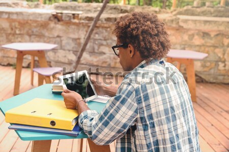 Back view of concenrated african man sitting and using tablet Stock photo © deandrobot