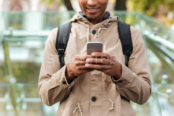 Cropped photo of cheerful dark skinned man using cellphone Stock photo © deandrobot