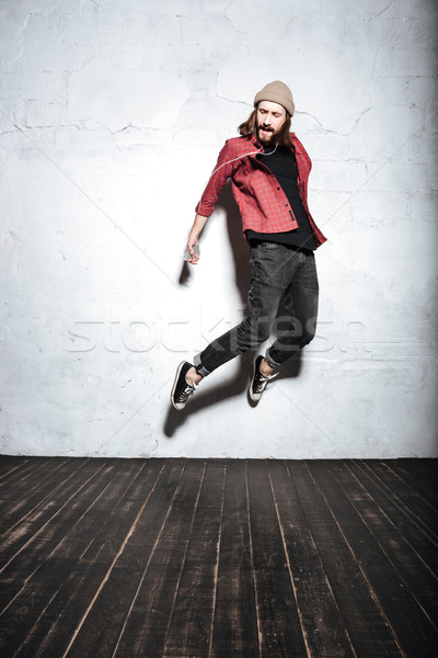 Picture of emotional young bearded hipster man jumping Stock photo © deandrobot