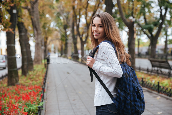 Cheerful attractive young woman with backpack walking in park Stock photo © deandrobot