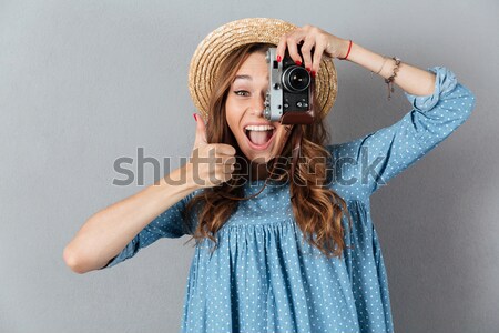 Portrait of a young smiling woman filming with retro camera Stock photo © deandrobot
