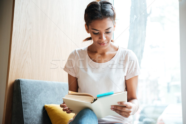 African woman reading book near the window Stock photo © deandrobot