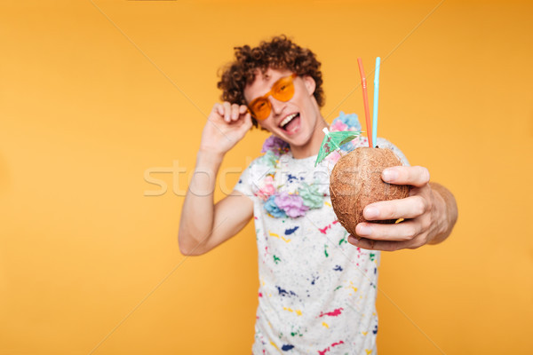 Stock photo: Happy young guy in sunglasses showing coconut cocktail