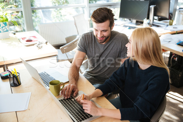 Happy young colleagues sitting in office coworking using laptop Stock photo © deandrobot