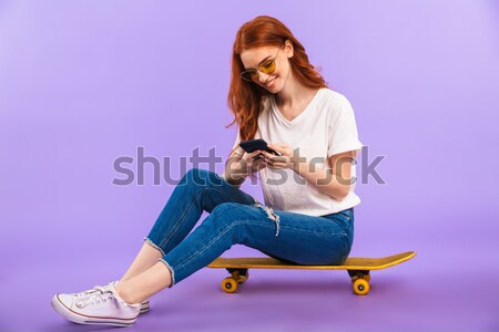 Young pretty woman sitting on skateboard isolated Stock photo © deandrobot