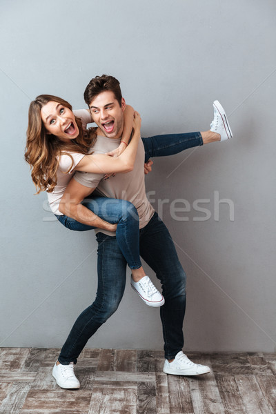 Full length portrait of an excited man carrying girlfriend Stock photo © deandrobot