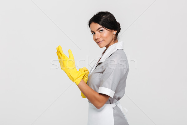 Portrait of young cheerful housekeeper wearing yellow rubber glo Stock photo © deandrobot