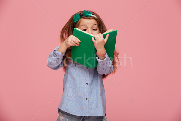 Image of amusing girl 5-6 years with long auburn hair reading in Stock photo © deandrobot