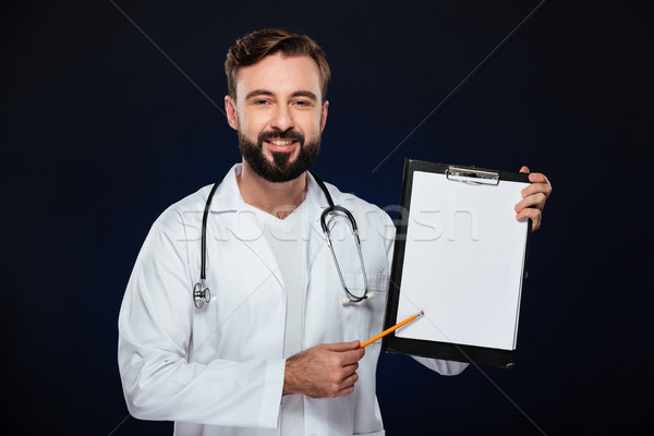 Portrait of a smiling male doctor dressed in uniform holding green apple and looking away at copy sp Stock photo © deandrobot