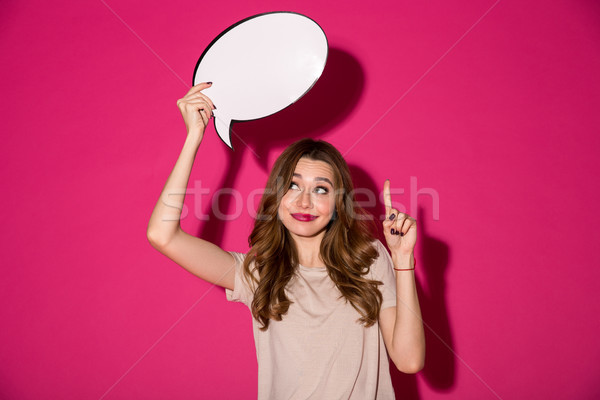 Cheerful pretty young woman holding speech bubble Stock photo © deandrobot