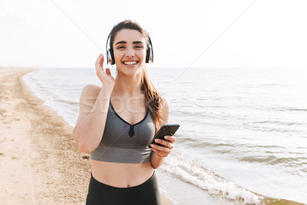 Heiter jungen Sportlerin läuft Strand Musik hören Stock foto © deandrobot