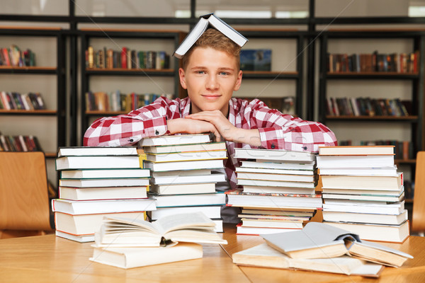 Smiling teenage boy sitting at the library table Stock photo © deandrobot
