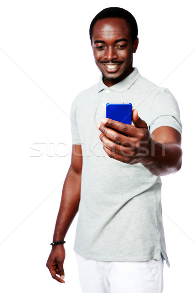 Portrait of a cheerful african man using smartphone over white background Stock photo © deandrobot
