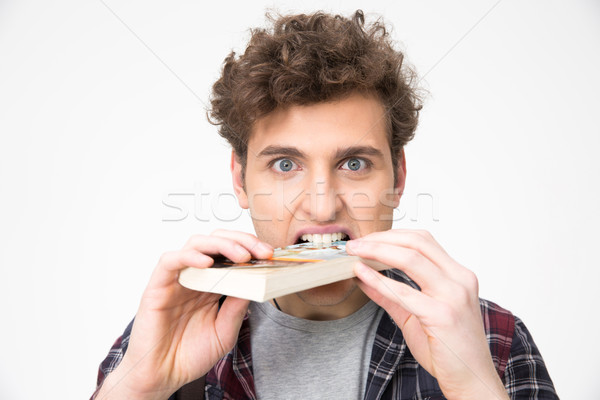 Handsome young man biting book over gray background Stock photo © deandrobot