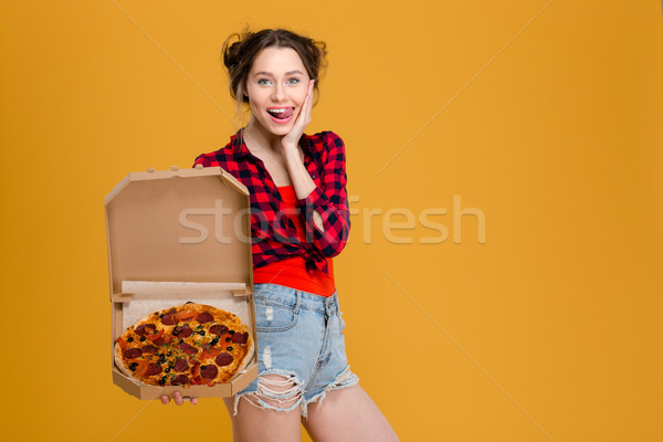 Stock photo: Amusing attractive young woman showing tongue and holding pizza