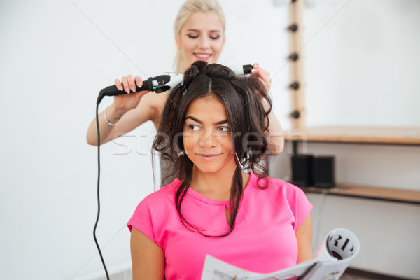 Woman hairdresser making hairdo using curling iron Stock photo © deandrobot