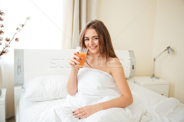 Femeie potabilă suc de portocale pat fericit acasă Imagine de stoc © deandrobot