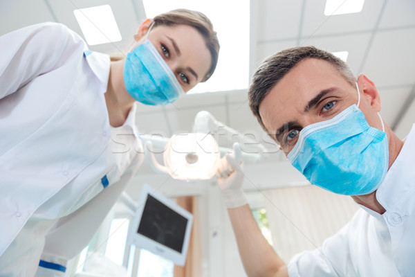 Two dentists making dental treatment to a patient Stock photo © deandrobot