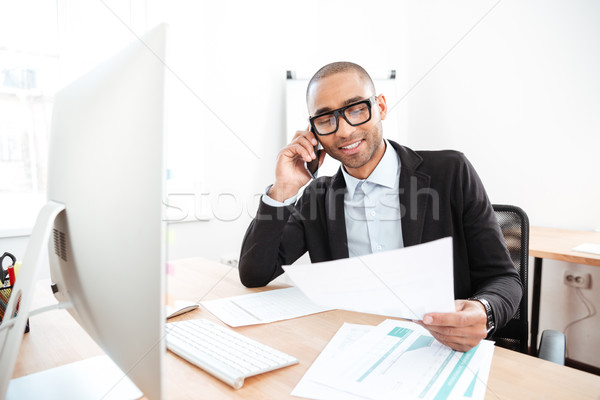 Office worker calling on the phone and reading business document Stock photo © deandrobot