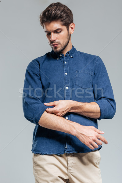 Portrait of a handsome serious man tacking sleeves isolated Stock photo © deandrobot