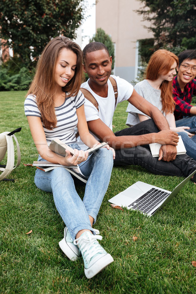 Happy people reading book and using laptop on lawn outdoors Stock photo © deandrobot