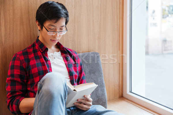 Asian student reading book in university library sitting on sofa Stock photo © deandrobot