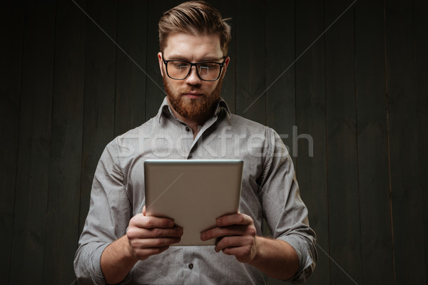 Concetrated bearded man in eyeglasses and shirt using tablet computer Stock photo © deandrobot