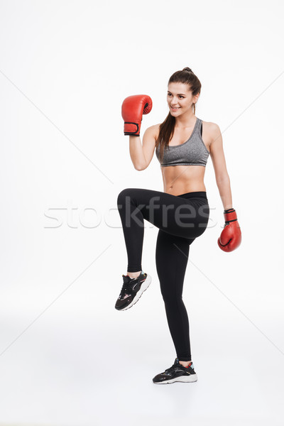 Woman wearing boxing gloves standing on foot with fist up Stock photo © deandrobot