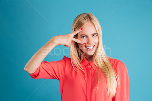 Portrait of a young smiling woman showing peace sign Stock photo © deandrobot