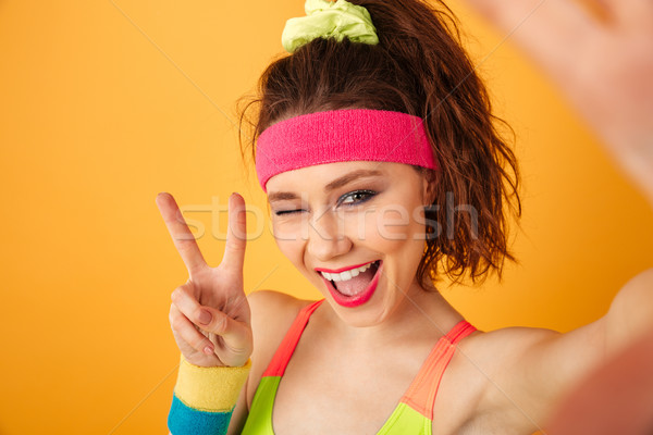Smiling fitness woman taking selfie, winking and showing peace sign Stock photo © deandrobot