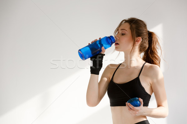 Serious young sports woman drinking water. Looking aside. Stock photo © deandrobot