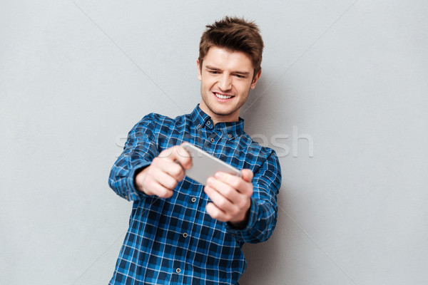 Man focused on game on smartphone Stock photo © deandrobot