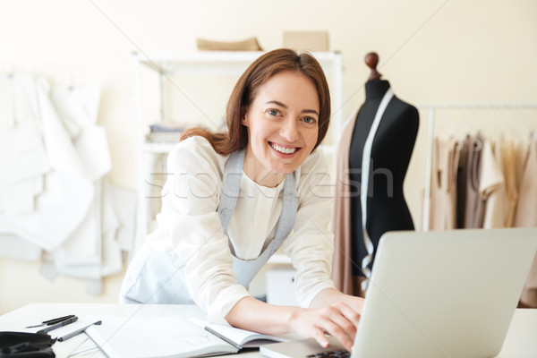 [[stock_photo]]: Utilisant · un · ordinateur · portable · travaux · souriant · brunette · bleu · tablier