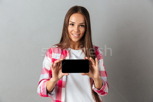 Portrait of a pretty smiling girl showing blank screen mobile ph Stock photo © deandrobot