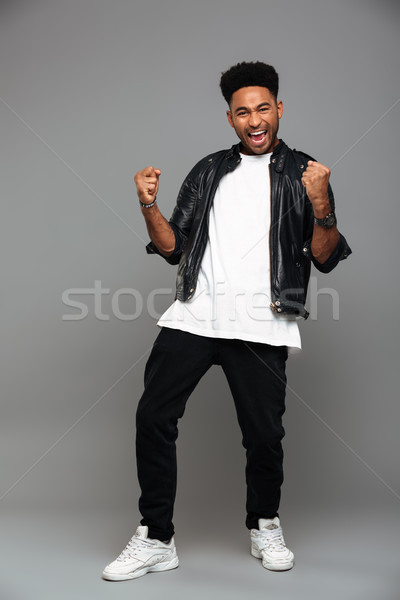 Full length photo of stylish afro american man clenching his fis Stock photo © deandrobot