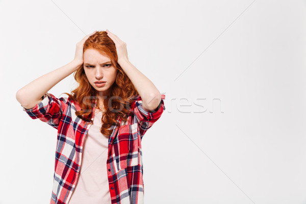 Confused ginger woman in shirt holding head and looking away Stock photo © deandrobot