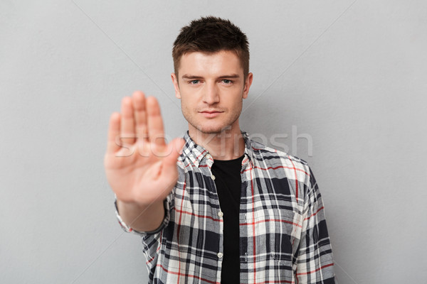 Portrait of a serious young man showing stop gesture Stock photo © deandrobot
