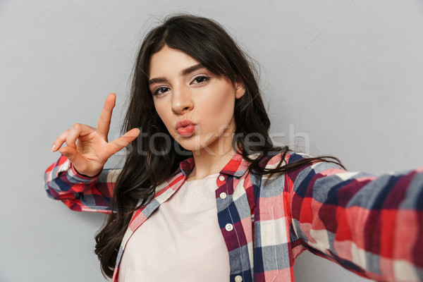 Cute beautiful young lady make selfie looking camera make peace gesture. Stock photo © deandrobot