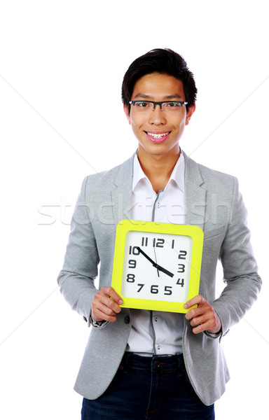 Young asian man holding a clock over white background Stock photo © deandrobot