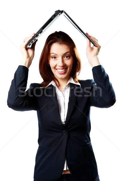 Smiling businesswoman holding a laptop above her head like a roof isolated on a white background Stock photo © deandrobot