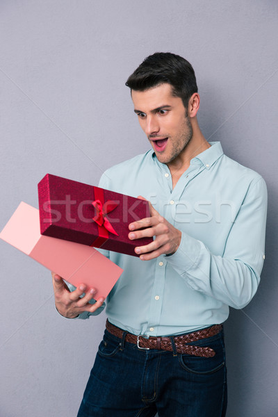 Foto stock: Feliz · joven · apertura · caja · de · regalo · gris · hombre